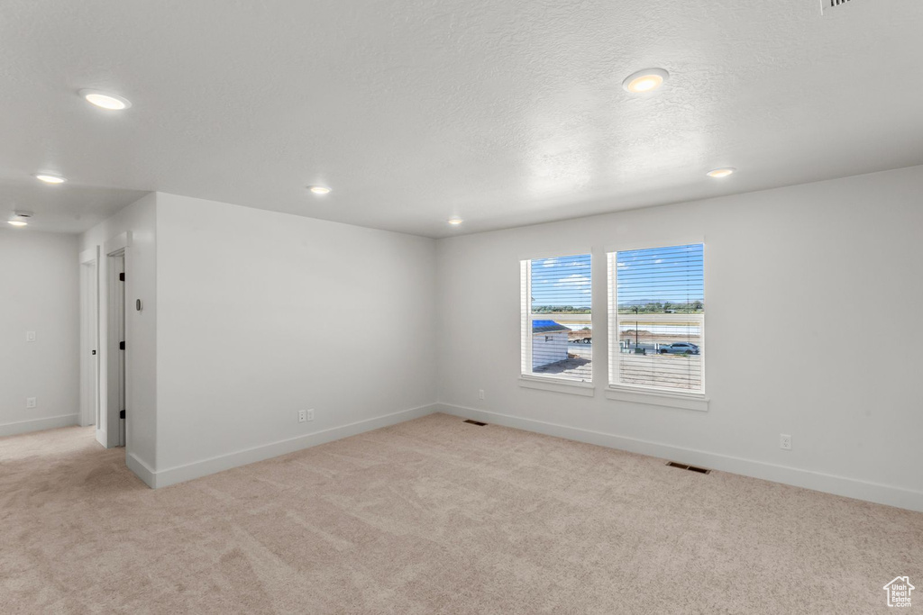 Empty room featuring light carpet, recessed lighting, and a textured ceiling
