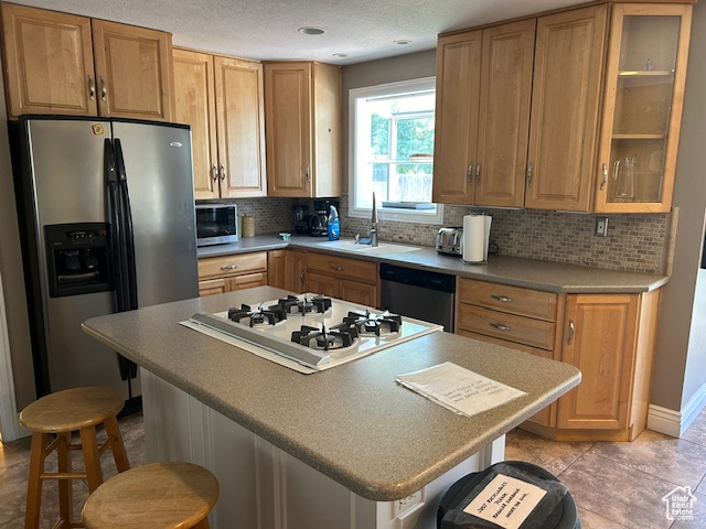 Kitchen with appliances with stainless steel finishes, a breakfast bar area, and tasteful backsplash