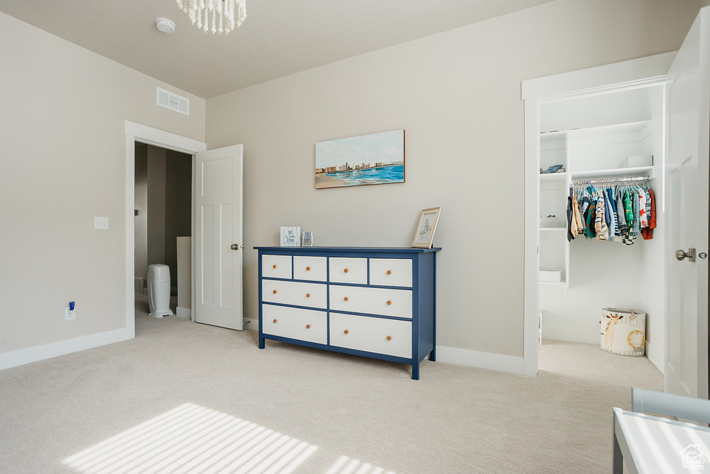 Carpeted bedroom with a chandelier and a spacious closet