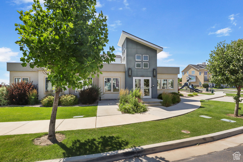 Contemporary home with stucco siding, a front yard, and a residential view