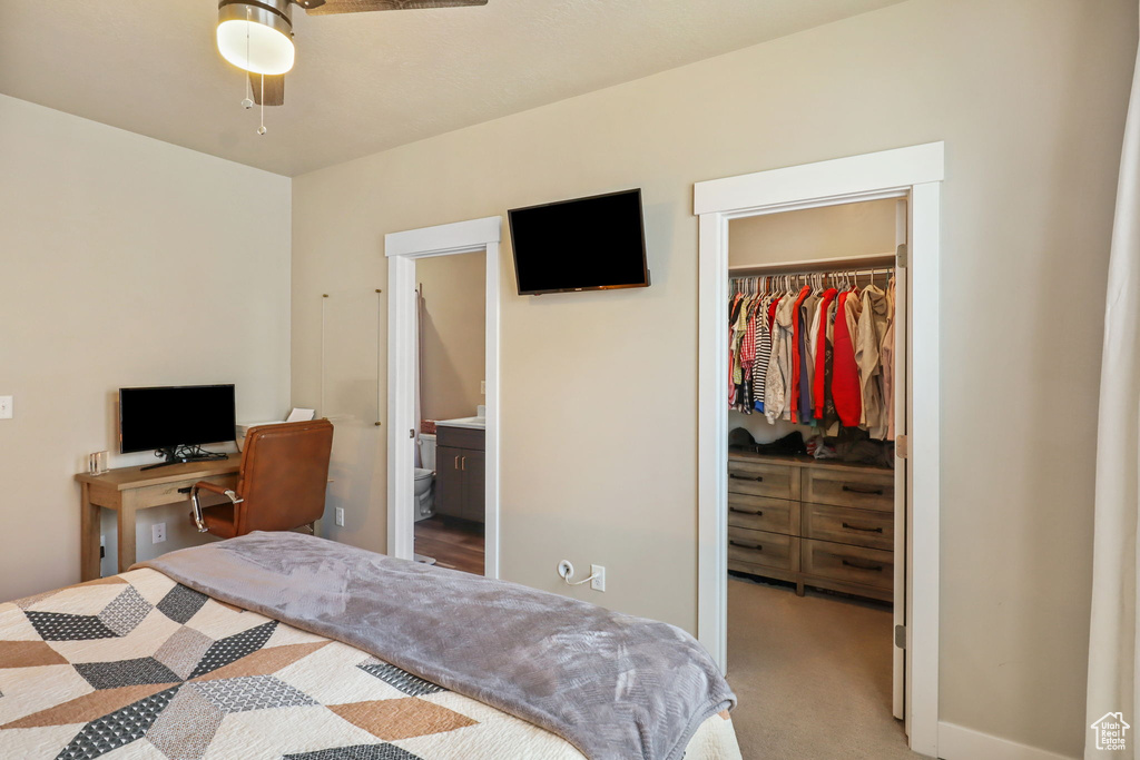 Bedroom with a spacious closet, a closet, light carpet, and ensuite bath
