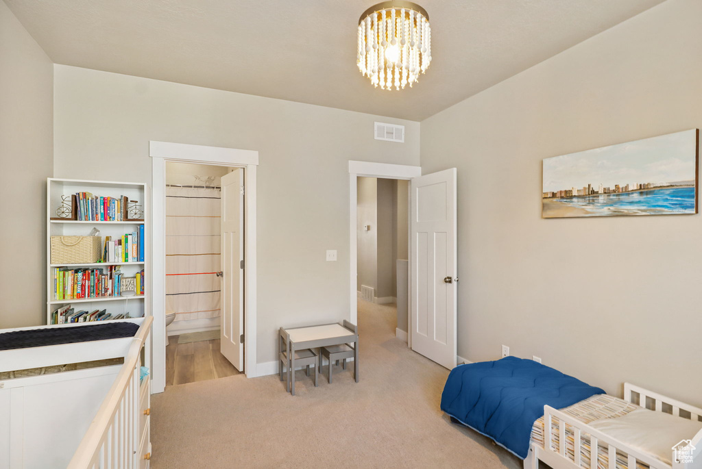 Bedroom with light carpet and a chandelier