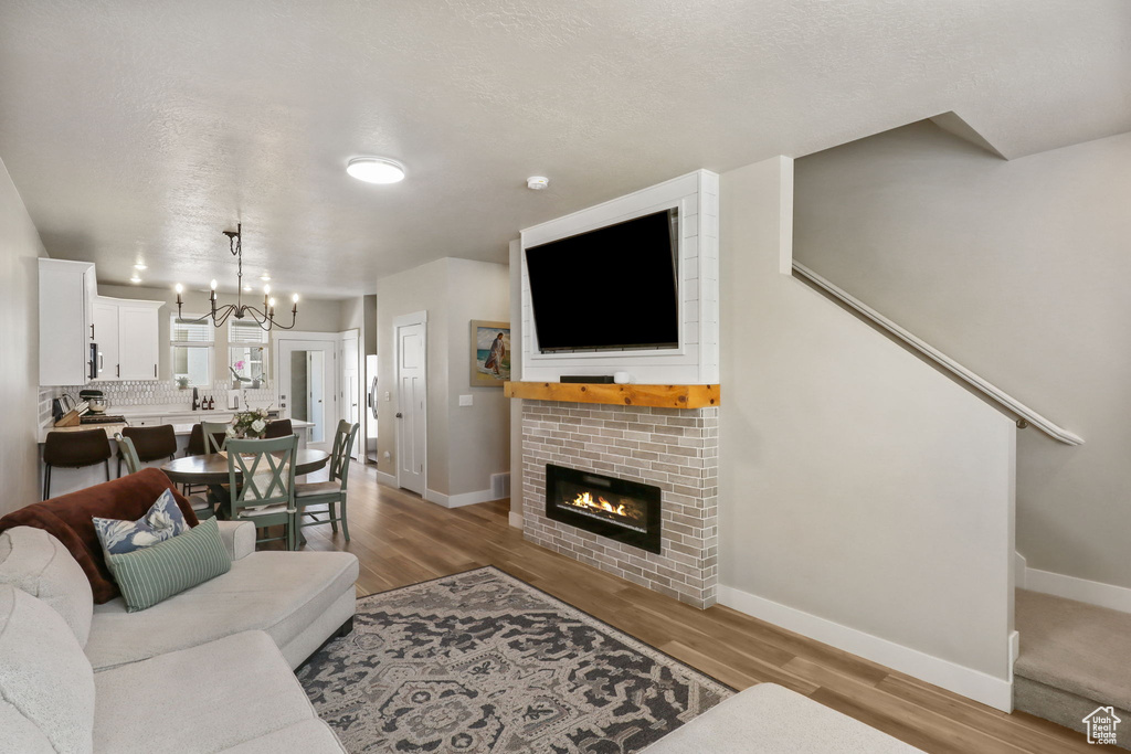 Living area featuring wood finished floors, a glass covered fireplace, and a chandelier