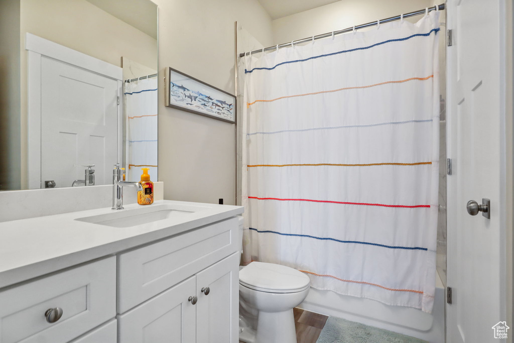 Full bathroom featuring vanity, shower / bath combination with curtain, and wood finished floors