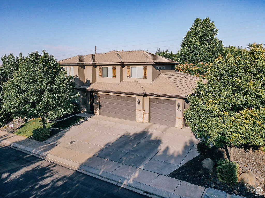 Traditional-style house featuring stucco siding, concrete driveway, a garage, stone siding, and a tile roof