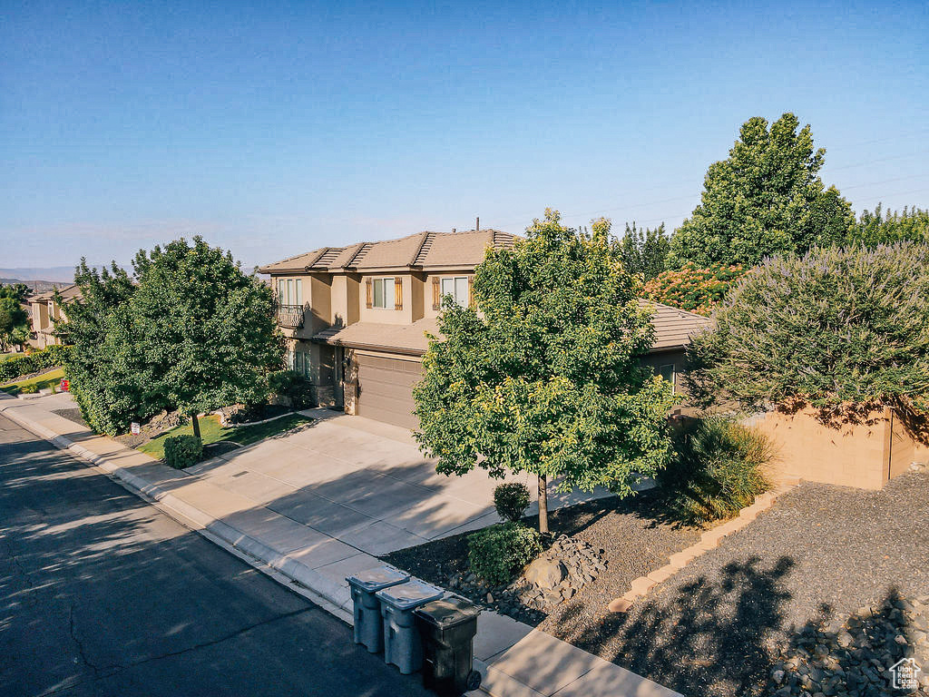 Obstructed view of property featuring driveway, a garage, a tiled roof, and stucco siding