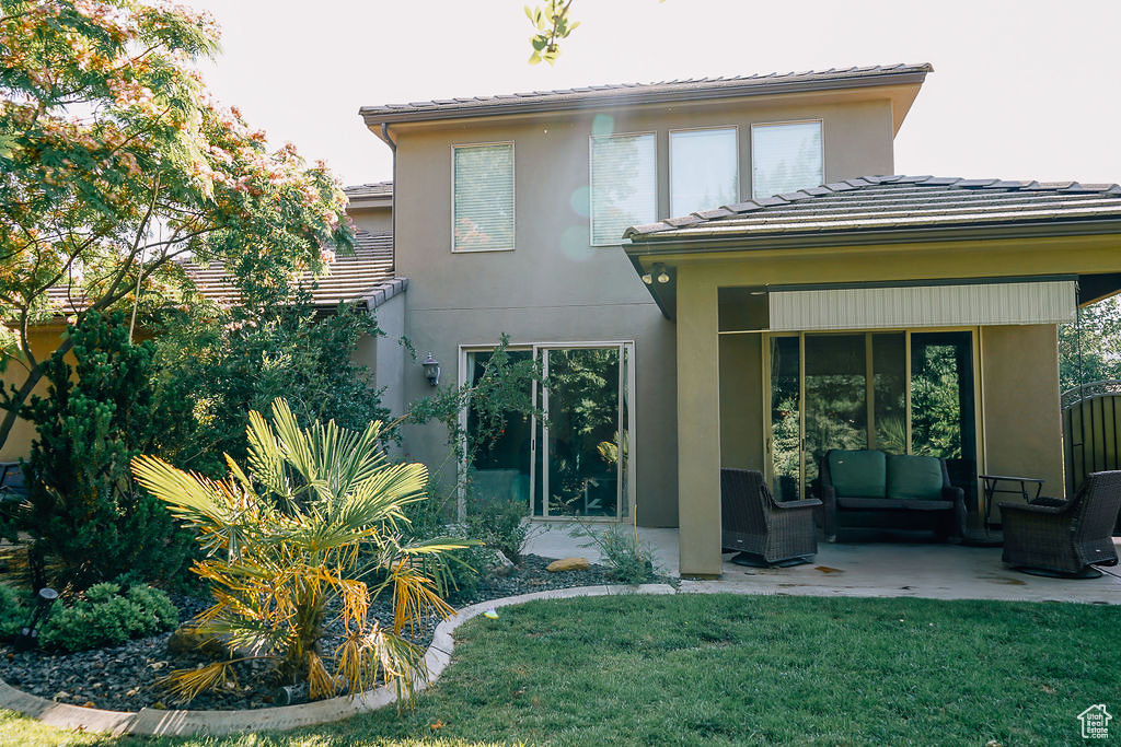 Back of house with outdoor lounge area, a patio, a yard, and a tiled roof