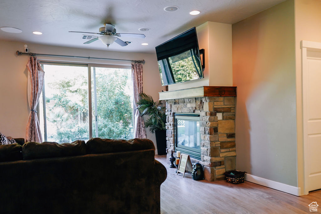 Living area with a ceiling fan, light wood-style flooring, a fireplace, and recessed lighting