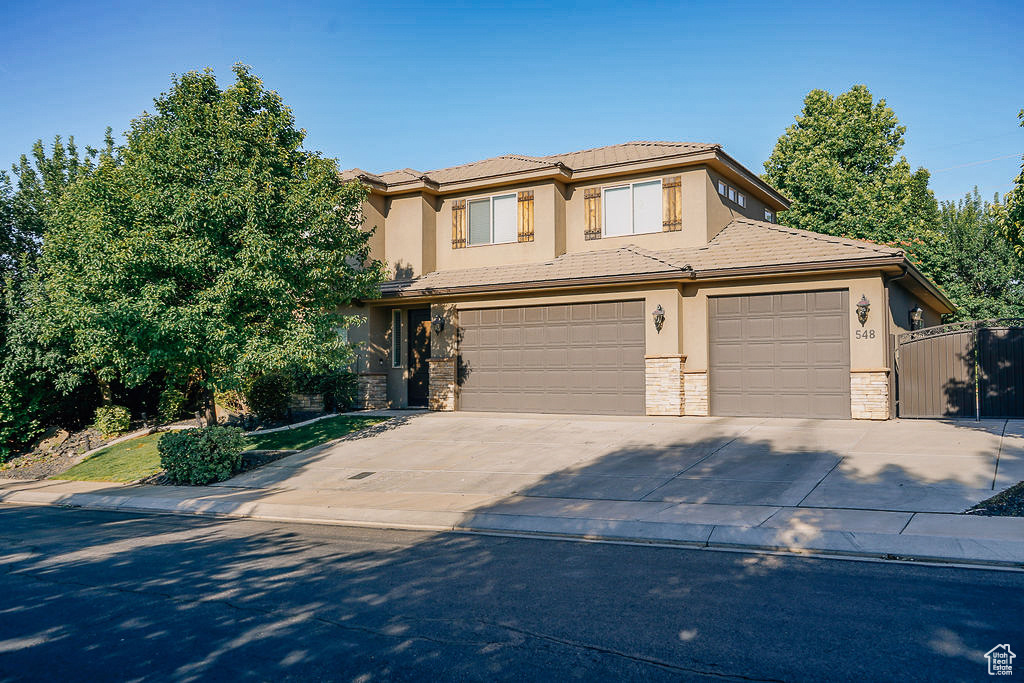 Prairie-style house with stucco siding, concrete driveway, stone siding, an attached garage, and a tile roof