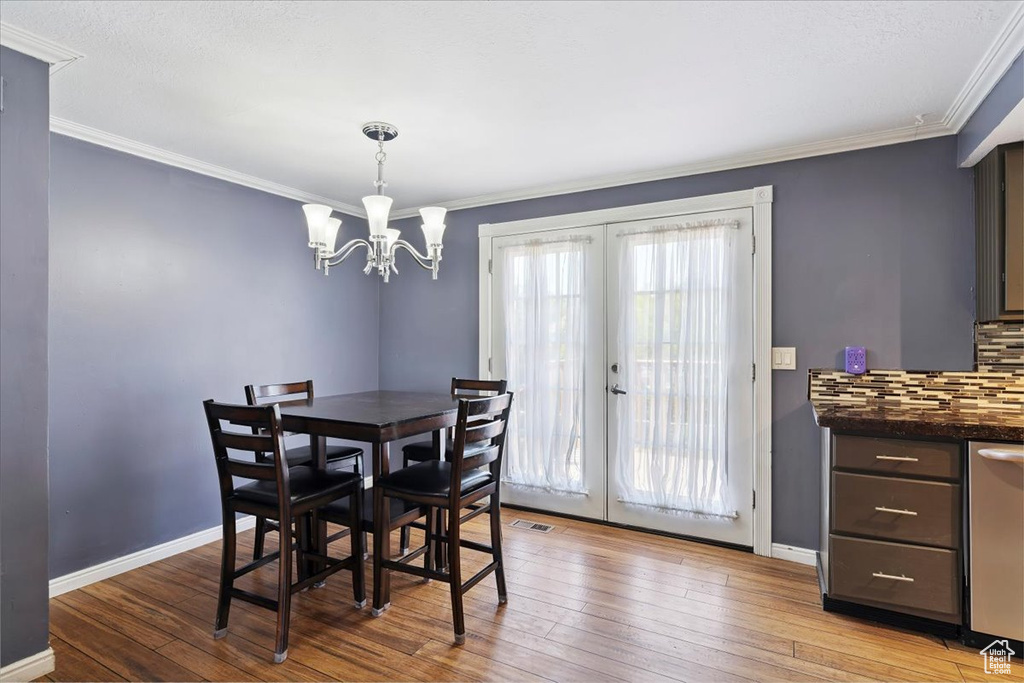 Dining area featuring french doors, crown molding, hardwood / wood-style floors, and a chandelier