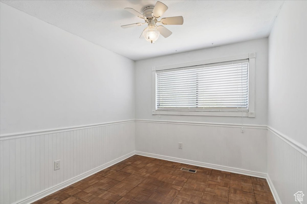 Spare room featuring ceiling fan and wainscoting