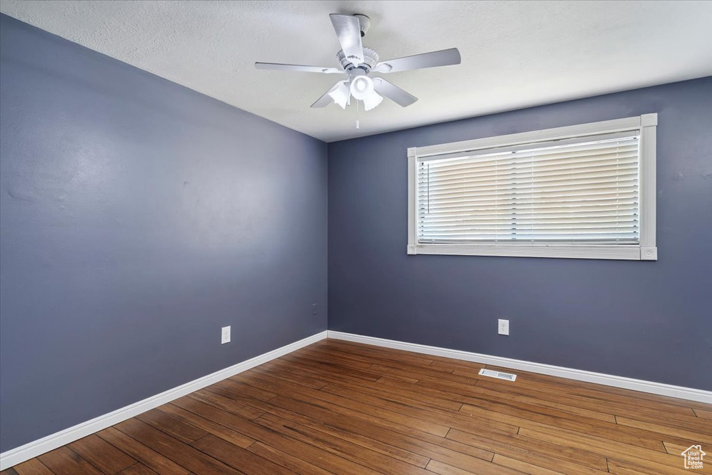 Empty room featuring a ceiling fan and hardwood / wood-style floors