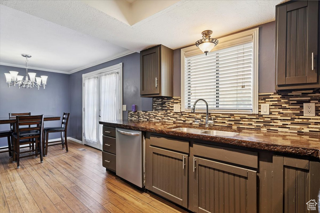 Kitchen featuring dishwasher, tasteful backsplash, ornamental molding, light wood finished floors, and dark stone counters