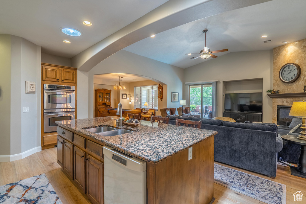 Kitchen featuring dishwasher, stainless steel double oven, arched walkways, dark stone countertops, and ceiling fan