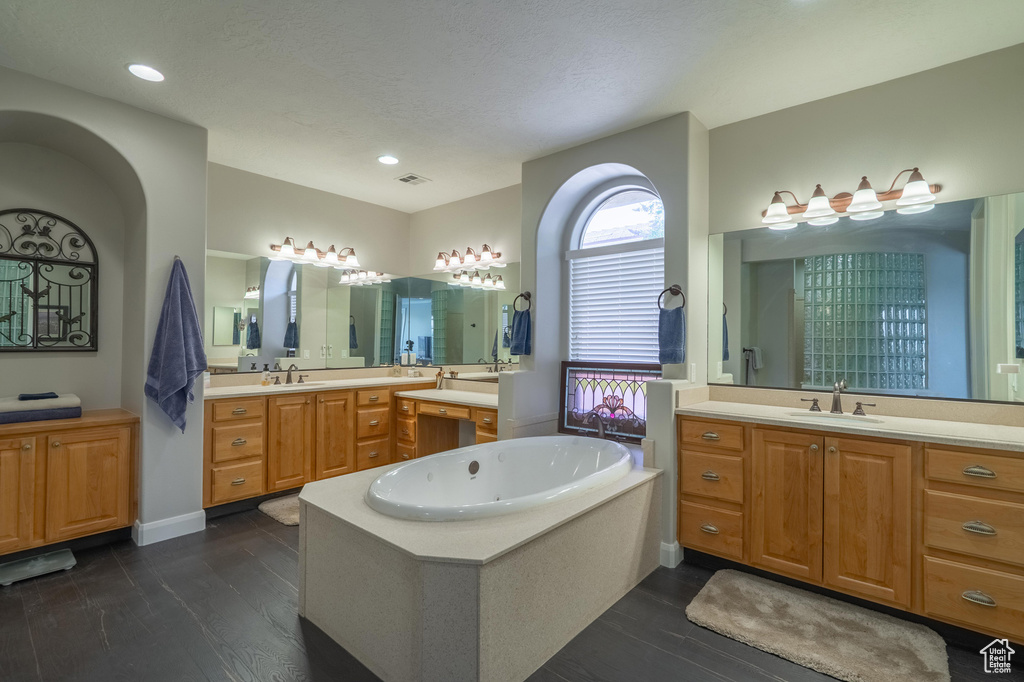 Full bathroom with two vanities, a garden tub, wood finished floors, and recessed lighting