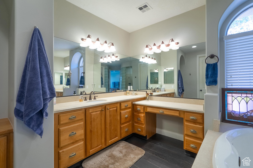 Full bath featuring vanity, a bath, and wood finished floors