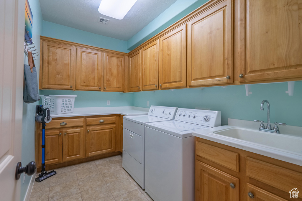Washroom featuring cabinet space, independent washer and dryer, and light tile patterned floors