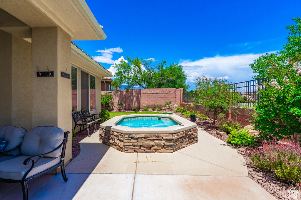 View of swimming pool featuring an outdoor hot tub, a patio area, and a fenced backyard