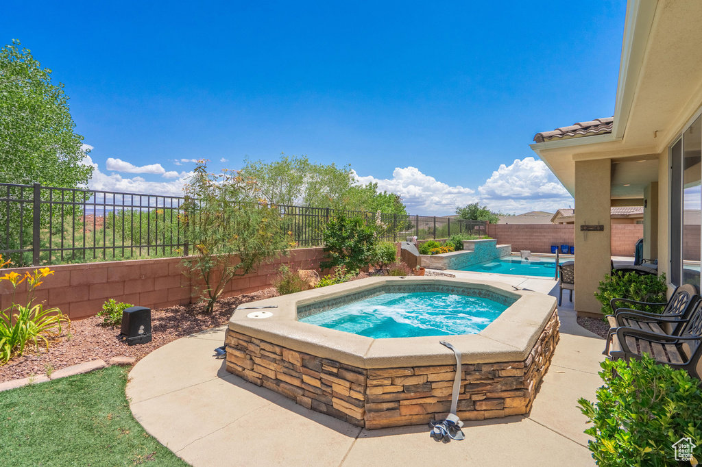 View of swimming pool with an in-ground hot tub, a fenced backyard, and a patio