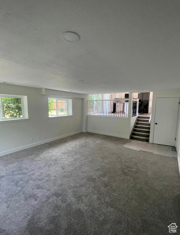 Carpeted empty room featuring a textured ceiling and stairway