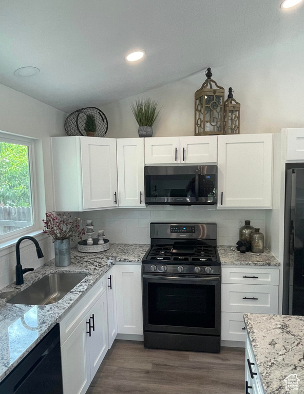 Kitchen featuring black appliances, white cabinets, backsplash, vaulted ceiling, and recessed lighting