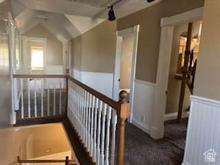 Stairs featuring a wainscoted wall, carpet floors, and vaulted ceiling
