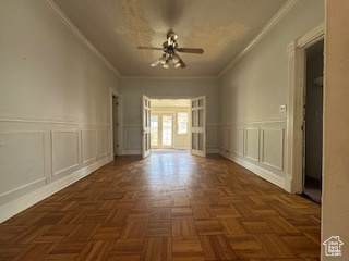 Spare room with a ceiling fan, ornamental molding, a decorative wall, and a wainscoted wall