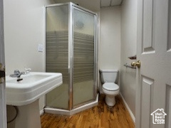 Bathroom featuring a shower stall, wood finished floors, and a paneled ceiling