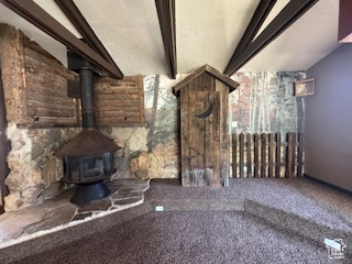 Unfurnished living room featuring carpet floors and a wood stove