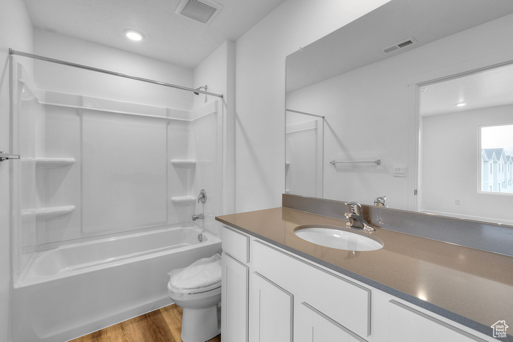 Bathroom with wood finished floors, vanity, bathing tub / shower combination, and recessed lighting