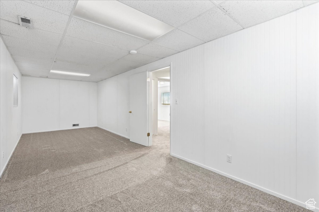 Carpeted empty room featuring a paneled ceiling and a smoke detector