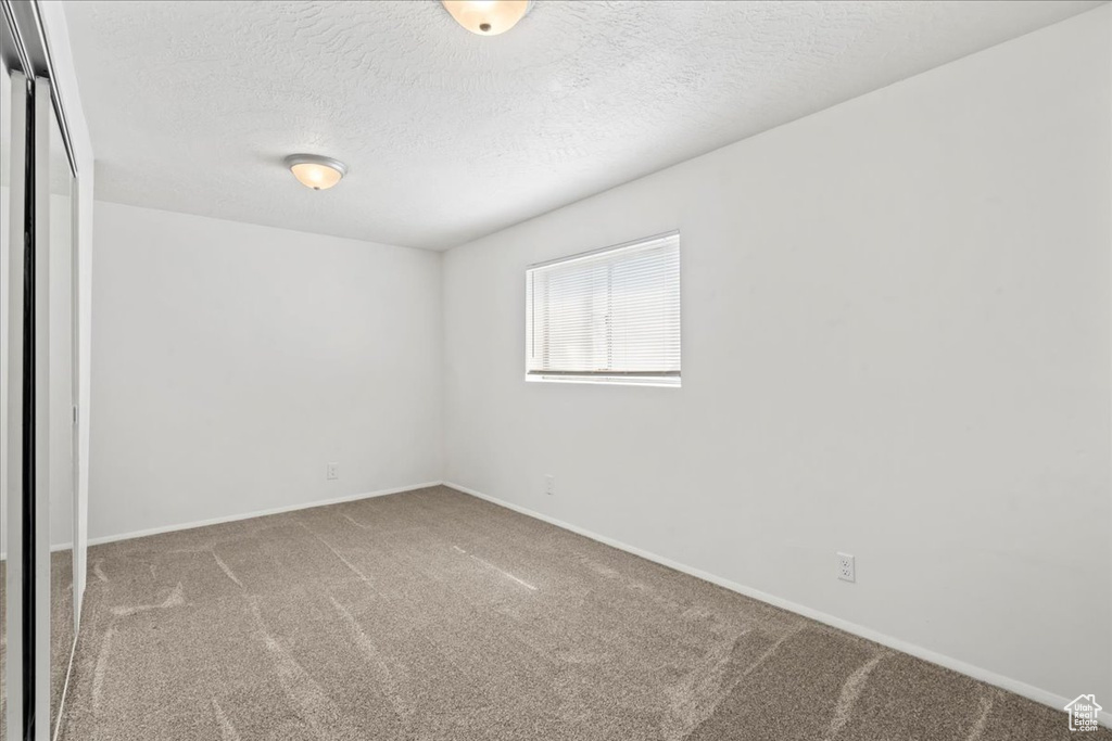 Carpeted empty room with a textured ceiling
