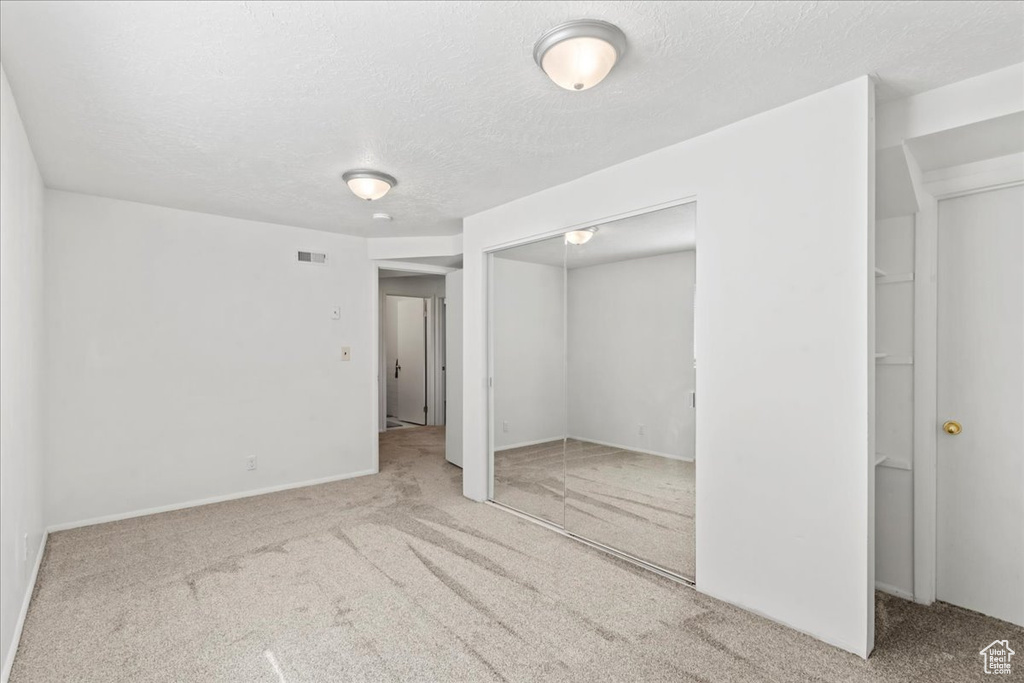 Unfurnished bedroom featuring carpet, a closet, and a textured ceiling
