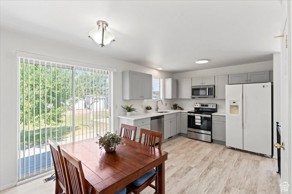 Kitchen with stainless steel appliances, gray cabinetry, light countertops, and light wood-style floors