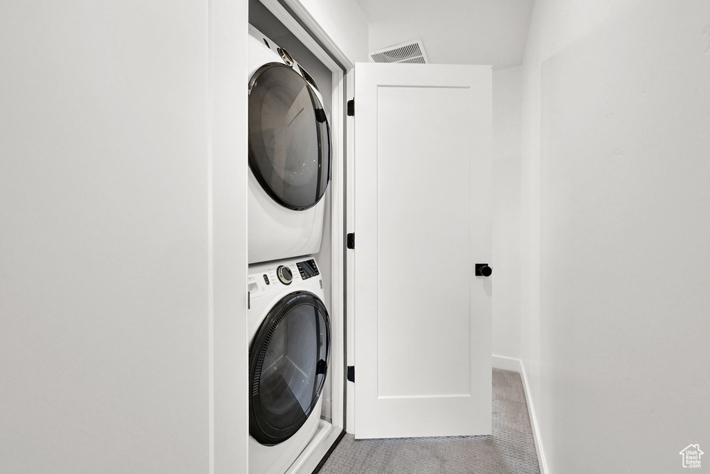 Laundry room featuring stacked washer and clothes dryer and carpet