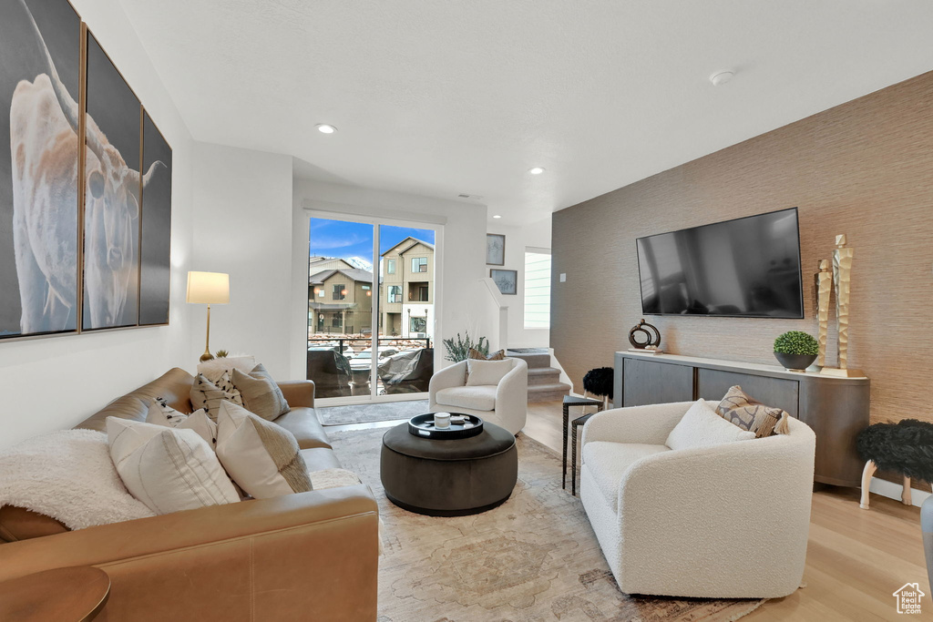 Living room featuring light wood-style flooring, recessed lighting, and an accent wall