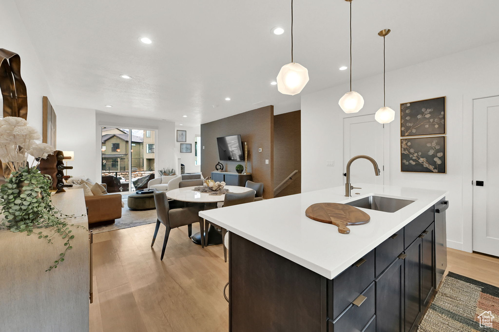 Kitchen with open floor plan, light countertops, light wood finished floors, recessed lighting, and a kitchen island with sink