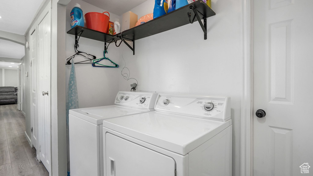 Washroom featuring washing machine and dryer and light wood finished floors