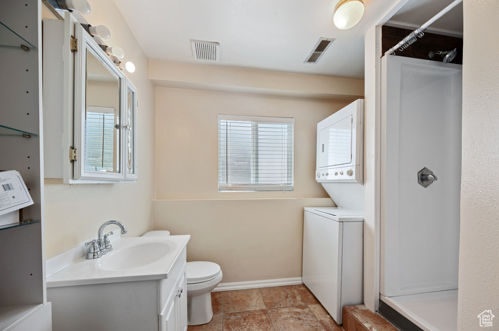 Bathroom with visible vents, plenty of natural light, and stacked washer / dryer