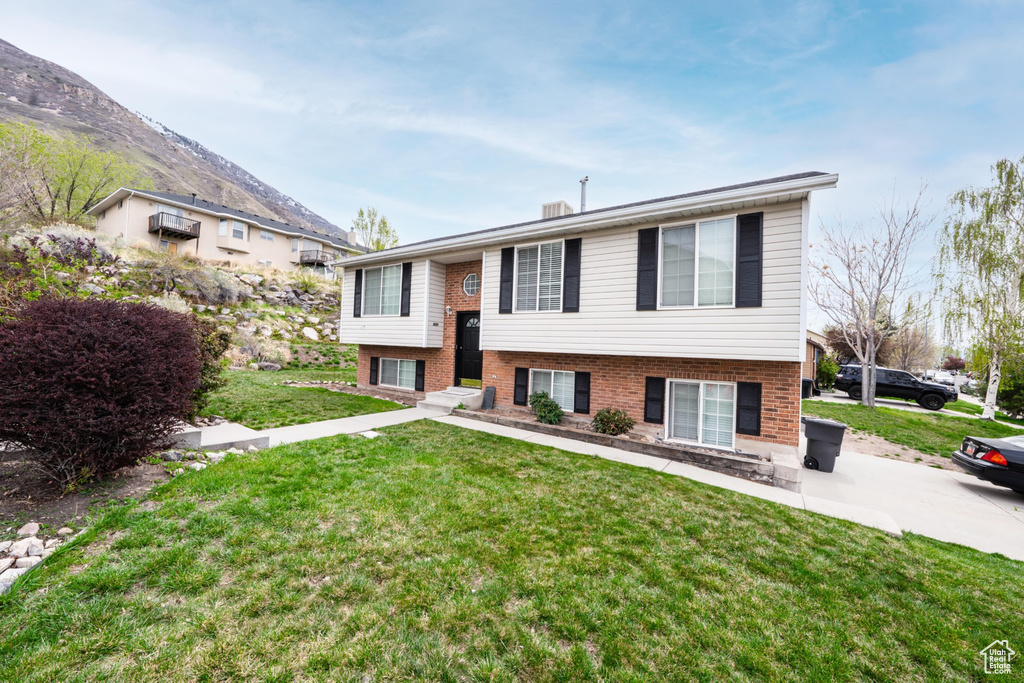 Split foyer home featuring a front yard, brick siding, and a mountain view
