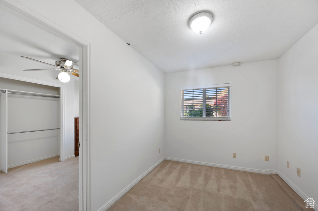 Unfurnished bedroom featuring a closet, baseboards, light colored carpet, and a textured ceiling