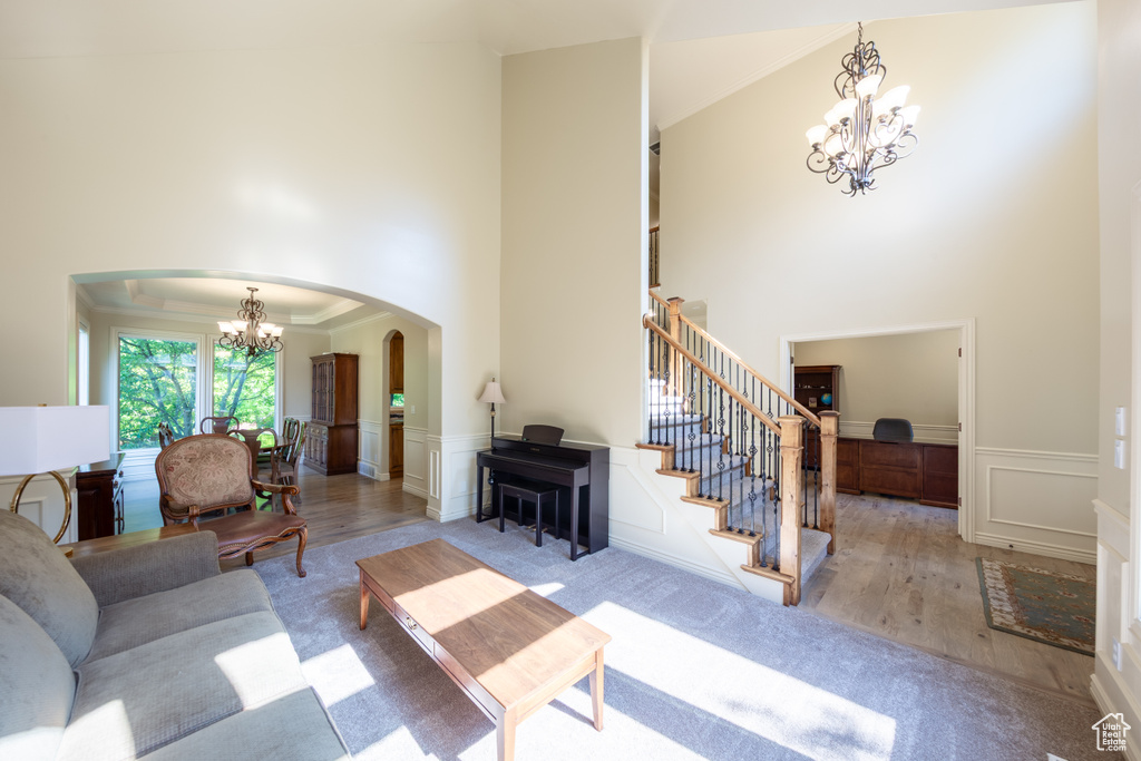 Living room with a chandelier, arched walkways, a high ceiling, a decorative wall, and stairs