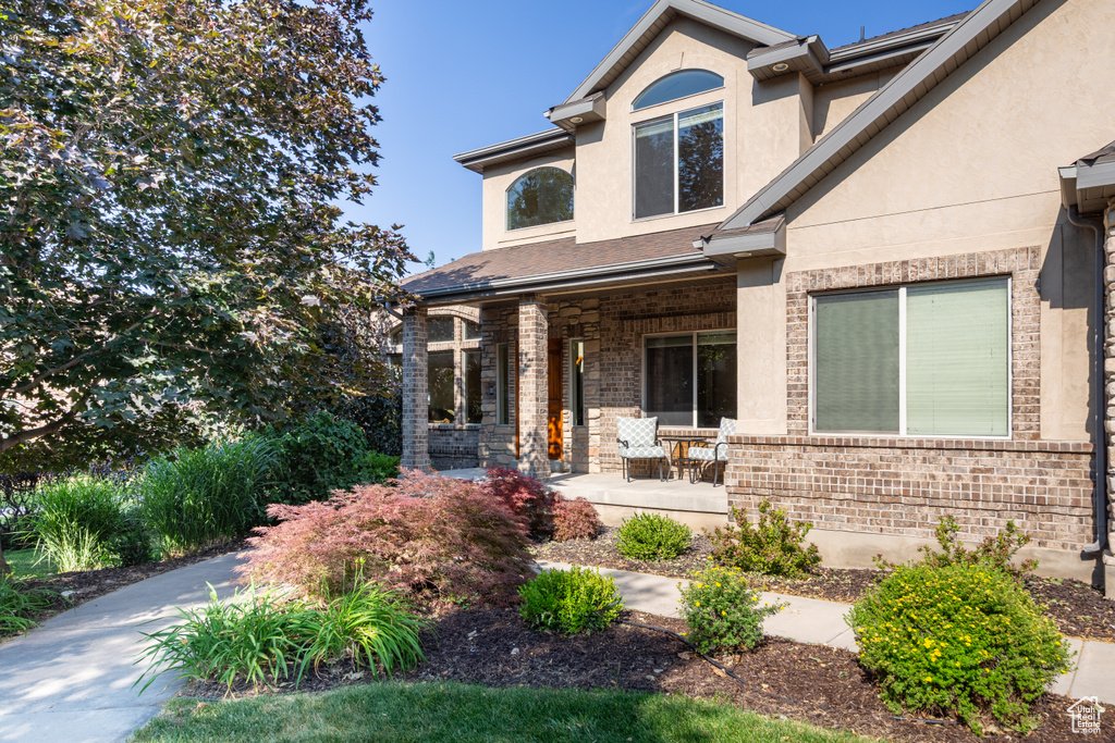 Traditional-style house with covered porch, stucco siding, and brick siding
