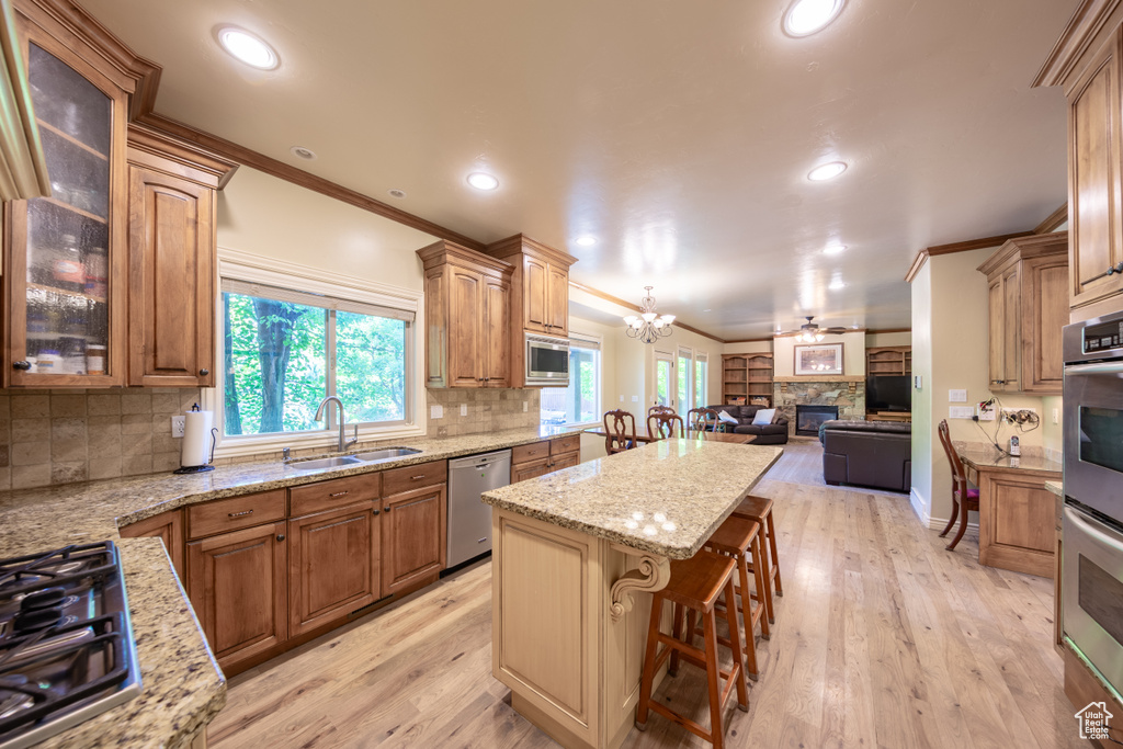 Kitchen with stainless steel appliances, a kitchen island, ornamental molding, open floor plan, and a fireplace