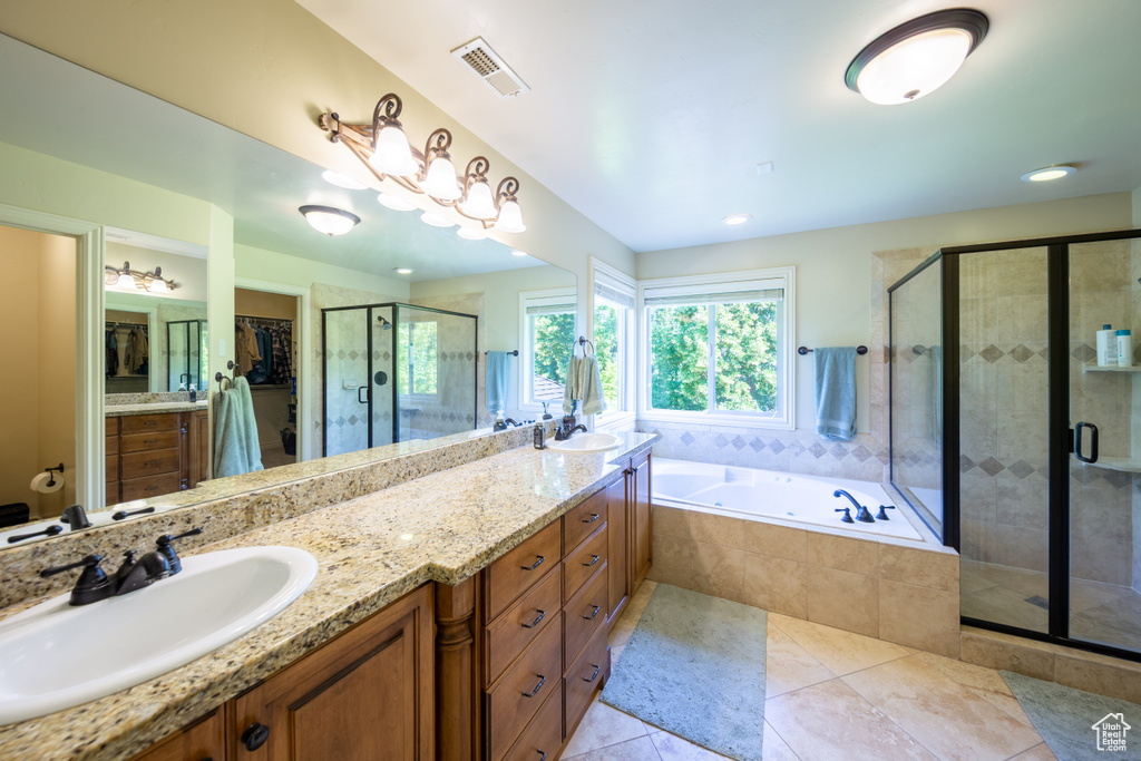 Full bath with double vanity, tile patterned floors, a shower stall, a garden tub, and a spacious closet