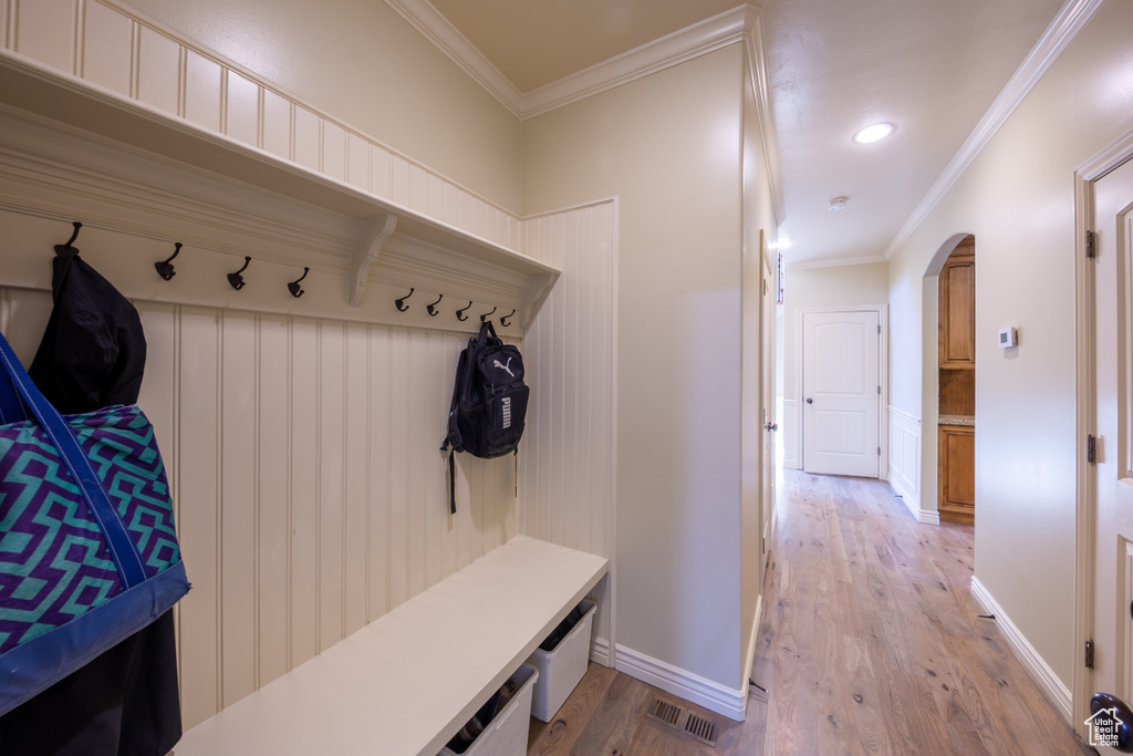 Mudroom with arched walkways, light wood-style floors, ornamental molding, recessed lighting, and wainscoting