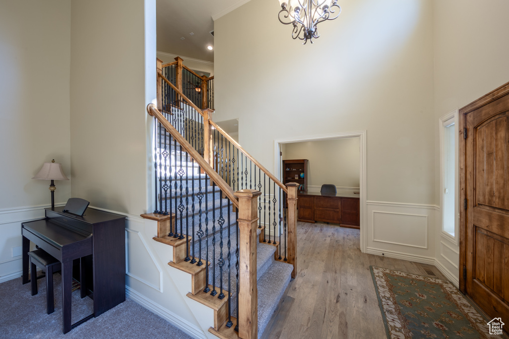Entryway with a decorative wall, stairway, a wainscoted wall, wood finished floors, and a chandelier