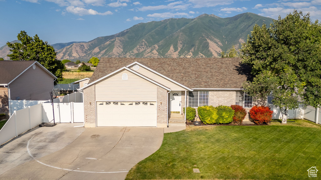 Ranch-style home featuring concrete driveway, brick siding, an attached garage, and a mountain view
