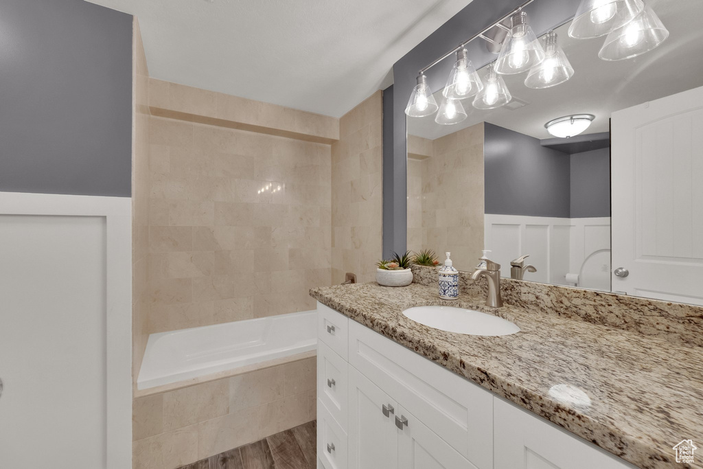 Bathroom featuring vanity, tiled shower / bath, and wood finished floors