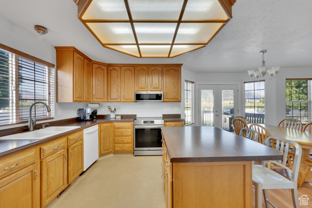 Kitchen featuring stainless steel appliances, dark countertops, a center island, a chandelier, and a breakfast bar area
